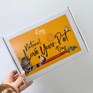 A box of Cosy Aromas wax melts with a 'National Love Your Pet Day' theme, featuring images of cats and a dog on the packaging.